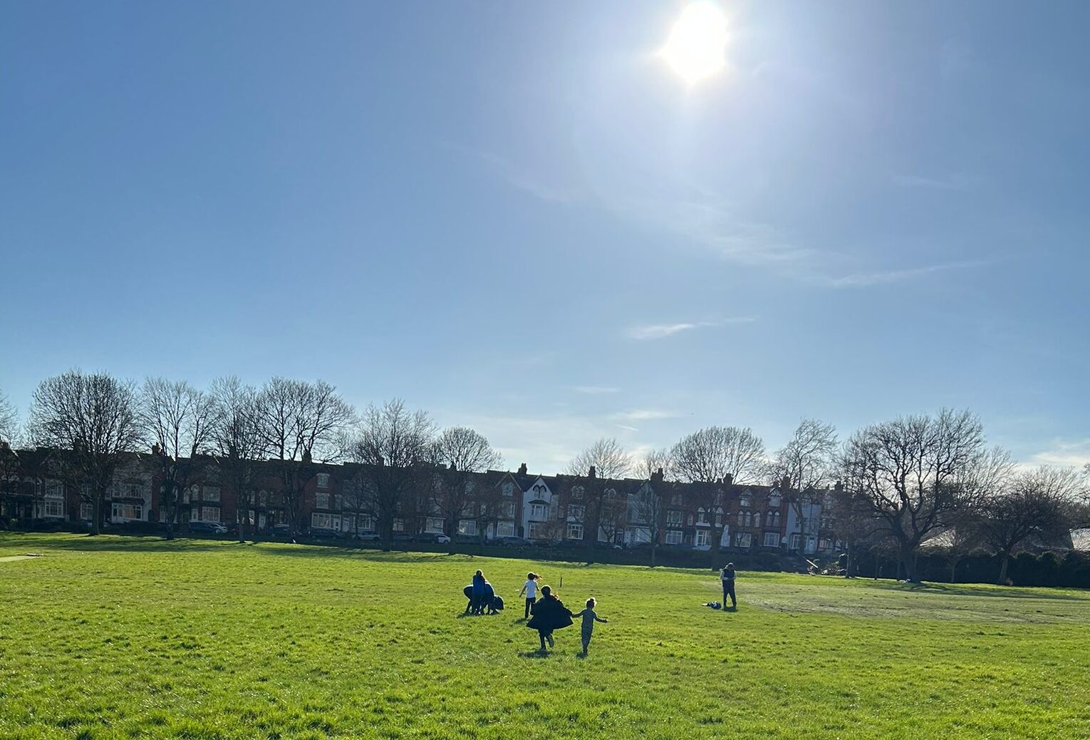 An urban park on a sunny day, with children running off to play